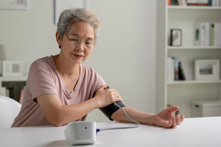 A senior woman is measuring blood pressure at home