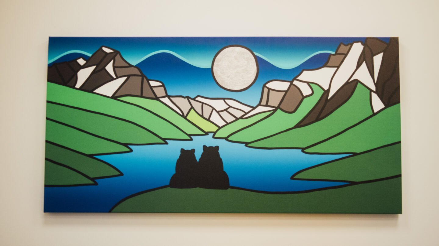 This is a close-up of the artwork titled Canoodling Bears By the Dancing Northern Lights, by Indigenous artist Jason Carter. Two bears appear to be cuddling by the lake and under a full moon.