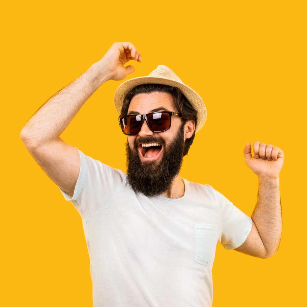 A man dances with his arms above his head while he wears sunglasses and a sunhat.