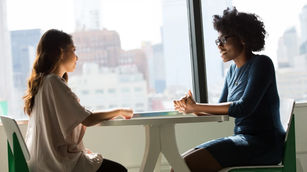 Two people sitting and talking together, representing the idea of team-base care.